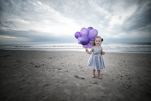 Little girl on the beach with purple balloons